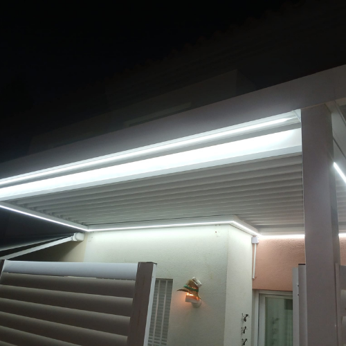 Vista general nocturna de pérgola bioclimática con iluminación LED perimetral instalada en vivienda unifamiliar.