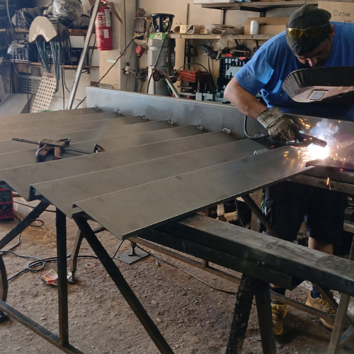 Soldadura y ensamblaje de paneles metálicos para valla en taller, proceso de fabricación a medida.