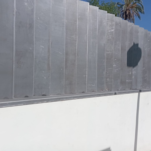 Paneles metálicos instalados sobre muro en obra, estructura preparada antes del lacado final.
