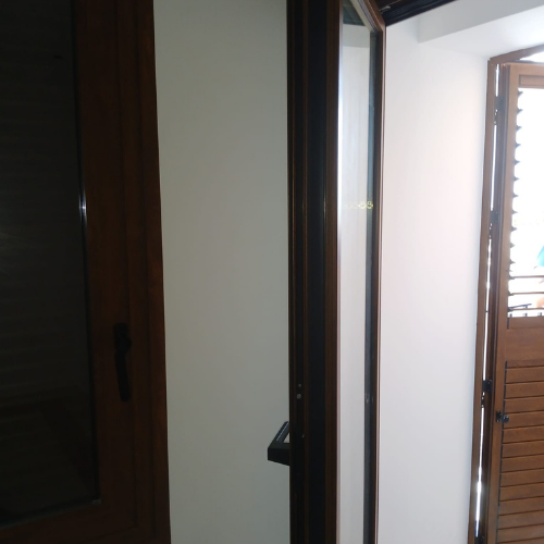 Detalle de marco y hoja en puerta de aluminio acabado imitación madera para vivienda.