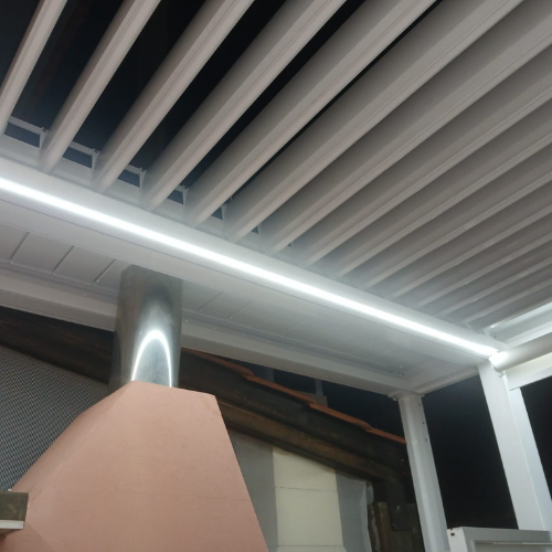 Pérgola bioclimática con lamas orientables en estructura de aluminio blanco instalada en vivienda unifamiliar.