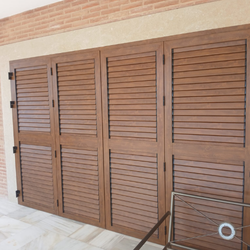 Contraventanas de aluminio imitación madera con lamas orientables instaladas en vivienda unifamiliar.