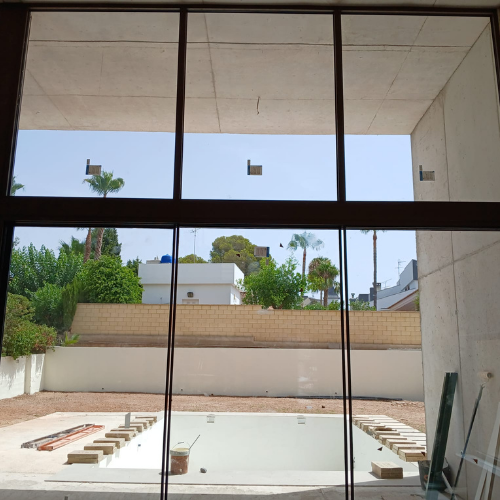 Cerramiento de aluminio con grandes superficies acristaladas y acabado en color bronce, visto desde el exterior.