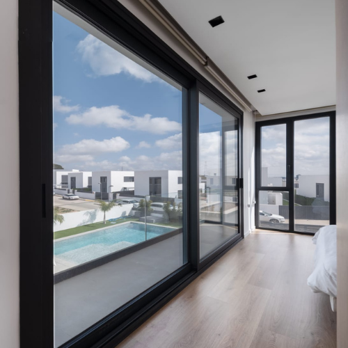 Ventanales de aluminio minimalista de suelo a techo con perfilería reducida en dormitorio de vivienda moderna.