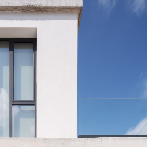 Puerta de entrada de gran formato en aluminio antracita con diseño minimalista y tirador integrado.