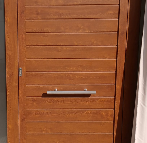 uerta de acceso a vivienda con acabado imitación madera instalada por Aluminis Samar